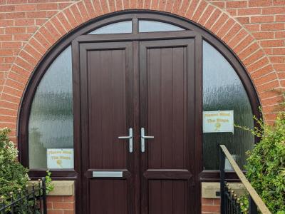 Mushroom top rosewood uPVC doors with tongue and groove panels and obscure double glazed glass for Carleton Memorial Hall.